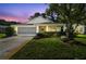 Charming single Gathering home with a well manicured lawn and screened garage at dusk at 11446 Sinatra Ct, New Port Richey, FL 34654