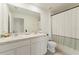 Bathroom featuring a dual sink vanity with white cabinets and a shower/tub combo with green and white shower curtain at 13734 Whiskey Daisy Dr, Dade City, FL 33525