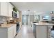 Modern kitchen with stainless appliances, white cabinetry, brick backsplash, and center island flowing into the living area at 13734 Whiskey Daisy Dr, Dade City, FL 33525