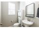 Modern half bathroom features a pedestal sink, sleek mirror and stylish fixtures at 17847 Althea Blue Pl, Lutz, FL 33558