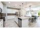 Bright kitchen boasts white cabinetry, stainless steel appliances, and an island with granite countertops at 17847 Althea Blue Pl, Lutz, FL 33558