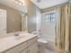 Bright bathroom with white vanity, sink, faucet, a large mirror, toilet, and bathtub with shower at 18002 Avalon Ln, Tampa, FL 33647