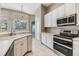 The kitchen has white cabinetry, stainless appliances, a tiled backsplash and view to outside at 18002 Avalon Ln, Tampa, FL 33647