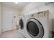 Bright laundry room with washer, dryer, wire shelves, beige tile floors, and a white door at 18002 Avalon Ln, Tampa, FL 33647