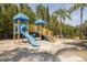 A well-maintained playground features a blue slide and yellow climbing structure, set in a sandy area with palm trees at 2722 Via Tivoli # 430A, Clearwater, FL 33764