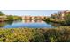 A serene pond reflects nearby buildings in this tranquil scene, with lush foliage in the foreground at 2722 Via Tivoli # 430A, Clearwater, FL 33764