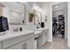 Bright bathroom featuring double sinks, rustic wood-trimmed mirrors, wood-look floors, and a walk-in closet at 3166 Francoa Dr, Odessa, FL 33556
