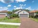 Charming single-story home featuring a brick driveway, manicured lawn, and lush landscaping at 3166 Francoa Dr, Odessa, FL 33556