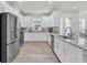 Open-concept kitchen boasts white cabinetry, granite countertops, stainless steel appliances, and wood-look tile flooring at 3166 Francoa Dr, Odessa, FL 33556