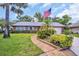 Charming brick home with a well-manicured lawn and an American flag waving proudly at 3224 Hilary Cir, Palm Harbor, FL 34684