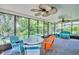 Screened patio featuring multiple ceiling fans, colorful seating, and views of the surrounding yard at 3224 Hilary Cir, Palm Harbor, FL 34684