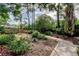 A beautiful backyard featuring lush landscaping, trees, walkway, and a cozy bench area at 3406 Hollyhock Way, Tampa, FL 33618