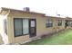 Back exterior view of a one-story home with windows, screen door, neutral siding, and a small green yard at 4736 Sunny Loop, Holiday, FL 34690