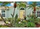 Charming home featuring a bright yellow front door surrounded by lush landscaping and beautiful palm trees at 500 Westborough Ln, Safety Harbor, FL 34695