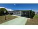 Exterior shot of the home with a carport, showcasing its white siding, green trim, and well-maintained lawn at 5318 Mary St, Zephyrhills, FL 33542