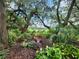 Beautiful landscaping includes flowerbeds and lush foliage underneath a canopy of mature trees at 5318 Mary St, Zephyrhills, FL 33542
