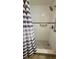 Close up view of tiled shower, with a shower curtain and safety bar at 5318 Mary St, Zephyrhills, FL 33542