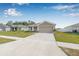 Inviting single-story home with a two-car garage, green lawn, and a long driveway under a blue sky at 6937 Gideon Cir, Zephyrhills, FL 33541