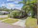 Cozy cottage-style home with a small front porch and mature landscaping and adjacent driveway at 702 W Virginia Ave, Tampa, FL 33603