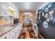 Galley kitchen featuring wood-look floors, white cabinets, stainless steel sink, and view to dining area at 7053 El Conquistador St, Zephyrhills, FL 33541