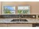 Close up of granite counters, stainless sink and gray tile backsplash with windows above at 834 26Th N Ave, St Petersburg, FL 33704