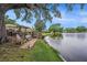 Picturesque backyard featuring a waterfront deck, mature oak tree, and serene lake views at 1179 Lazy Lake W Rd, Dunedin, FL 34698