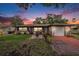 Charming single-story home featuring a well-manicured lawn, inviting fountain, and cozy exterior lighting at 1179 Lazy Lake W Rd, Dunedin, FL 34698