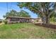 Beautiful single-story home with lush lawn, mature trees, and a charming water fountain focal point at 1179 Lazy Lake W Rd, Dunedin, FL 34698