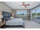 Serene bedroom featuring a wood accent wall, ceiling fan, and sliding glass doors that open to the pool area at 1228 Dartford Dr, Tarpon Springs, FL 34688