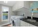 Bright laundry room features white cabinets, dark countertops, washer, dryer, and a scenic view outside the window at 1228 Dartford Dr, Tarpon Springs, FL 34688