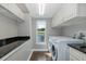 Functional laundry room with lake view, white cabinetry, dark countertops, washer, and dryer at 1228 Dartford Dr, Tarpon Springs, FL 34688