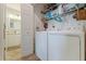 Practical laundry room featuring a modern washer and dryer, storage shelves, and a glimpse into the adjacent bathroom at 12321 Sun Vista W Ct # 52, Treasure Island, FL 33706