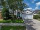 Charming single-story home featuring a well-manicured lawn, mature trees, and an attached two-car garage at 12713 Whitney Meadow Way, Riverview, FL 33578