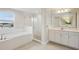 Bright bathroom featuring a soaking tub, glass-enclosed shower, and double sink vanity at 13137 Wellspring Dr, Lithia, FL 33547