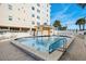 A beautiful community pool on a sunny day with lounge chairs and well-maintained surroundings at 13440 Gulf Blvd # 501, Madeira Beach, FL 33708