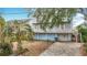 Three-story waterfront home shows balconies, garage access, and tropical landscaping in the yard at 13918 Raie Ave, Hudson, FL 34667