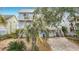 Waterfront home with a paved driveway offers dual balconies and garage with tropical landscaping in the front yard at 13918 Raie Ave, Hudson, FL 34667