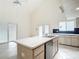 Bright kitchen features a vaulted ceiling, white cabinets, an island, and sliding doors to the outside at 13918 Raie Ave, Hudson, FL 34667