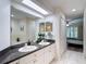 Bathroom featuring double sink vanity, granite counters, and entrance to a shower at 1628 Lullwater Ln, Lutz, FL 33549