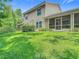 Exterior view of the home's well-manicured lawn, neutral siding, and screen doors that create the perfect outdoor oasis at 1628 Lullwater Ln, Lutz, FL 33549