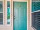 Close-up of the turquoise front door and adjacent windows, with natural light at 1628 Lullwater Ln, Lutz, FL 33549