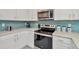 Kitchen features stainless steel appliances, white cabinets and beautiful backsplash at 16892 Delia St, Wimauma, FL 33598