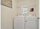 Bright laundry room equipped with modern white appliances and ample shelving at 16892 Delia St, Wimauma, FL 33598