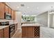 Modern kitchen with wood cabinets, stainless steel appliances, center island, and open view to the living room at 19106 Beckett Dr, Odessa, FL 33556