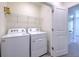 Convenient laundry room with a white washer and dryer, shelving and a closed door at 2882 Peony Prairie Ln, Wesley Chapel, FL 33543