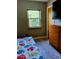 Neutral bedroom with a colorful comforter, wood dresser, television, and natural light from the window at 307 Druid Hills Rd, Temple Terrace, FL 33617