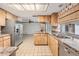 Functional kitchen with wooden cabinets, stainless steel appliances, and view into the bright living area at 3230 Player Dr, New Port Richey, FL 34655