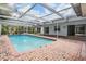 Beautiful in-ground pool surrounded by a screened enclosure and brick patio, perfect for relaxation at 3230 Player Dr, New Port Richey, FL 34655