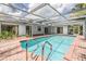 Inviting in-ground pool with screened enclosure, brick patio, and lush landscaping, ideal for outdoor fun at 3230 Player Dr, New Port Richey, FL 34655