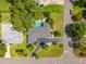 Overhead shot of a property with a pool, lush lawn, mature trees, and a dark driveway at 3236 San Pedro St, Clearwater, FL 33759
